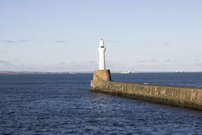 Lighthouse by sea against sky