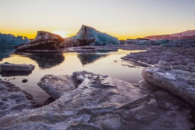 Rock formations in sea against sky during sunset