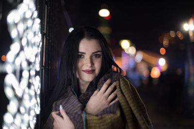 Close-up of young woman in city at night