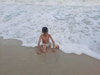 Full length of shirtless boy on beach