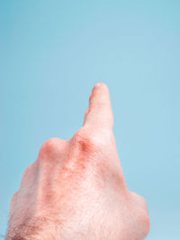 Close-up of person hand against blue sky