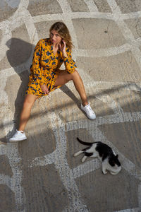 High angle portrait of young woman sitting with cat on walkway 