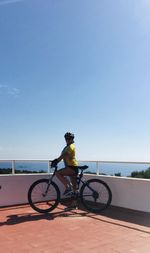 Man riding bicycle against clear blue sky