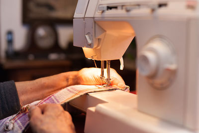 Cropped hands of woman using sewing machine at workshop