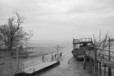 People on shore by sea against sky