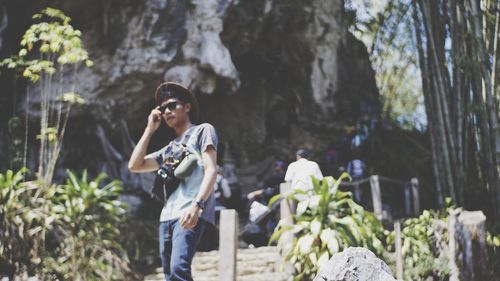 Young woman standing on rock against plants