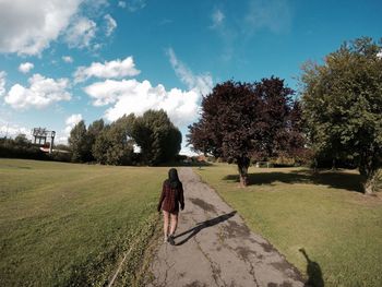 Rear view of woman walking on landscape against sky