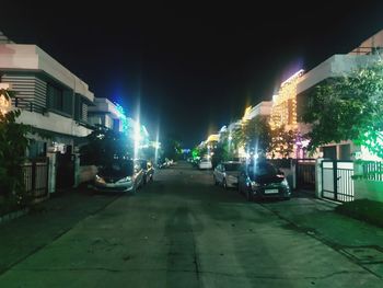 Cars on illuminated street amidst buildings in city at night