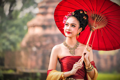 Beautiful young woman wearing traditional clothing while holding umbrella