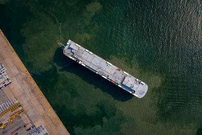 Aerial view of roro vehicle carrier vessel parking for loading car at sea port.