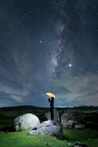 Man standing on rock against sky at night