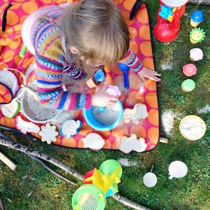 High angle view of girl playing with sand and toys on grass