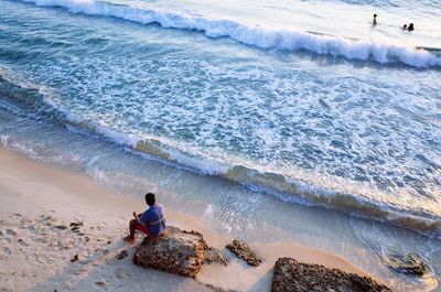 Rear view of men sitting at beach