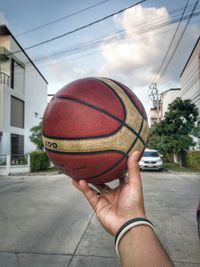 Close-up of hand holding ball against building in city