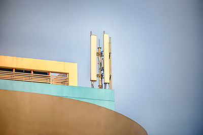 Low angle view of communication equipment on building terrace against sky