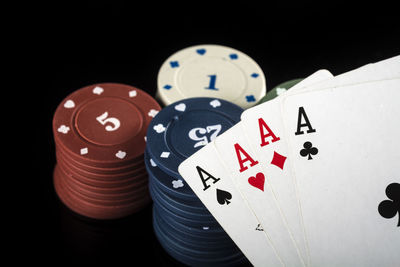 Close-up of gambling chips and cards on black background