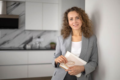 Portrait of young woman using digital tablet while standing in office