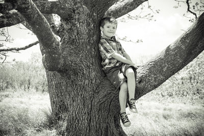 Portrait of boy sitting on branch