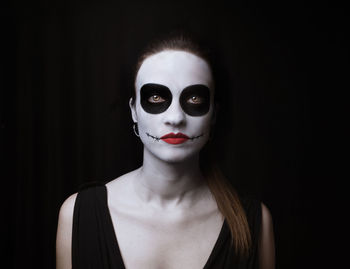 Portrait of woman wearing face paintagainst black background