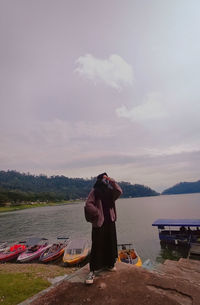 Rear view of man looking at lake against sky