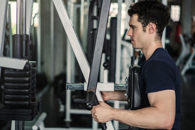 Man lowering weight of fitness machine and working out in the fitness gym.