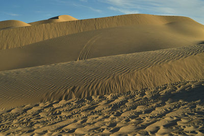 Scenic view of sand dunes at beach against sky