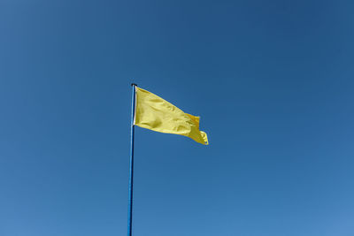 Low angle view of flag against blue sky