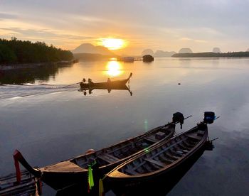 Boats moored in lake against sky during sunset