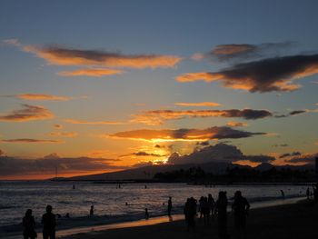 Silhouette people standing on beach against sky during sunset