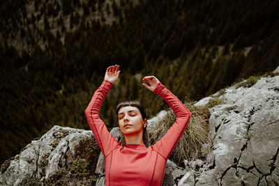 High angle view of woman with arms raised lying on mountain