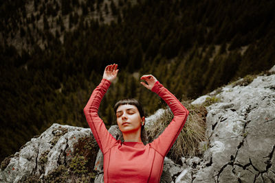 Portrait of woman with arms raised on mountain