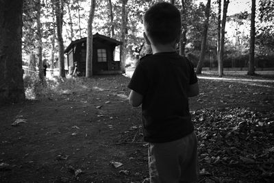 Rear view of boy standing in forest