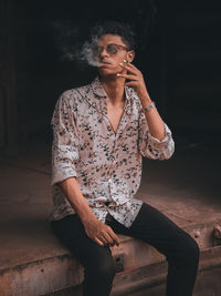 Young man looking away while sitting on floor