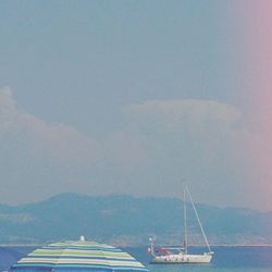 Boats in sea against cloudy sky