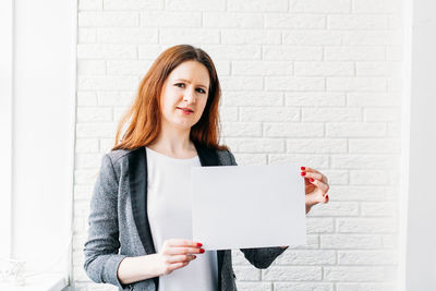 Portrait of a smiling young woman standing against wall