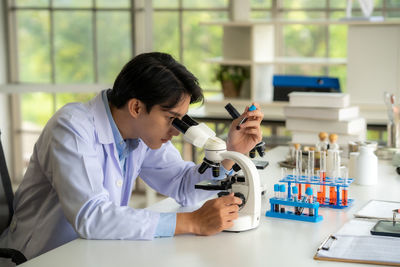 Side view of young woman using mobile phone in laboratory