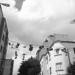 Low angle view of shoes tied on cables by buildings in city