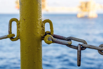 Close-up of chain on railing against sea