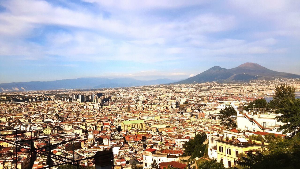 building exterior, architecture, built structure, mountain, cityscape, residential district, crowded, mountain range, sky, high angle view, residential structure, townscape, residential building, town, city, house, cloud - sky, community, human settlement, roof