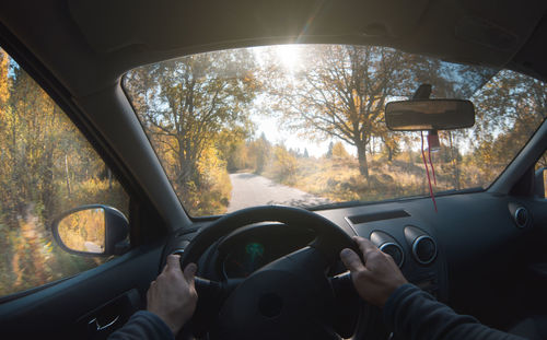 A man drives a car on a forest road in the autumn forest. point of view