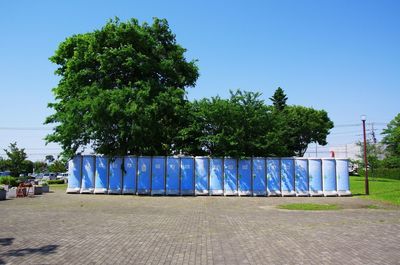 Empty street amidst trees against clear blue sky