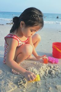 Side view of girl making sandcastle at beach