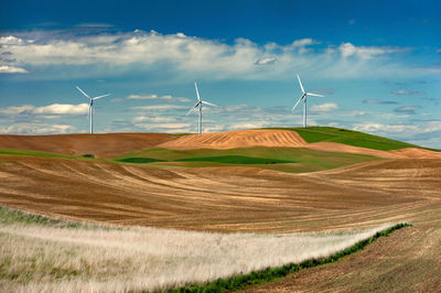 Wind turbines on field against sky