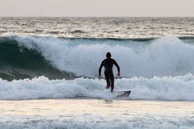 Man surfing in sea against sky