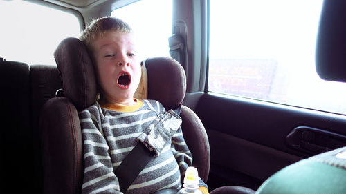 Portrait of boy yawning in car