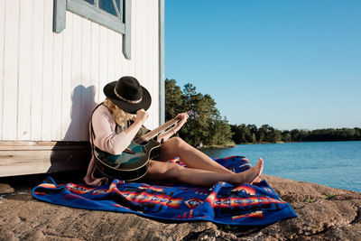 Midsection of woman sitting on seat against sky