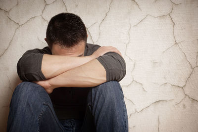 Depressed man sitting against wall