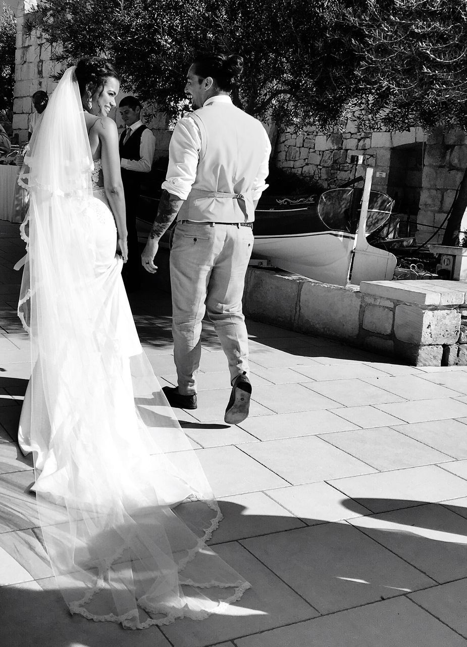 REAR VIEW OF COUPLE STANDING ON STREET