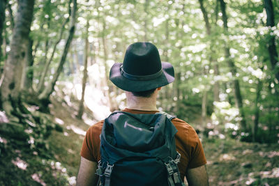 Hiker with black hat walking through a mediterranean forest