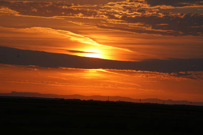 Scenic view of silhouette field against romantic sky at sunset